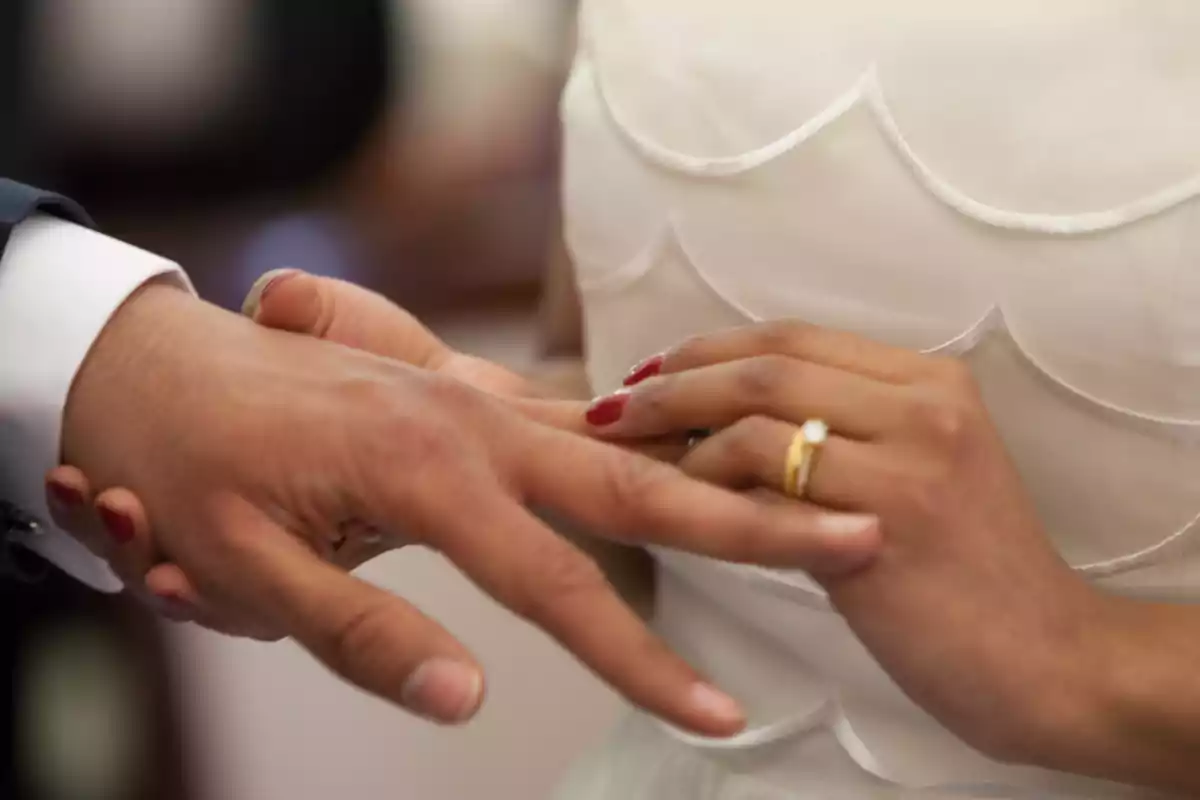 Mano de una mujer colocando un anillo en el dedo de un hombre durante una ceremonia de boda