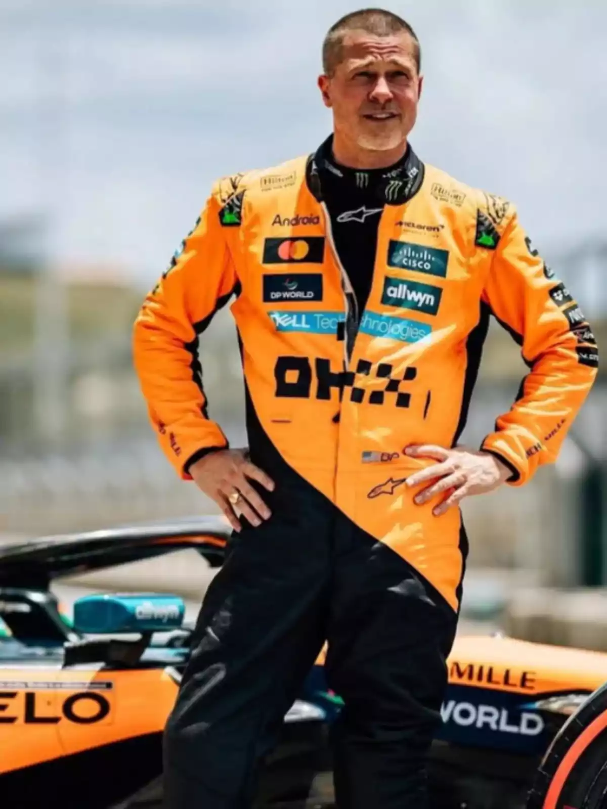Motorsport driver in an orange and black suit posing next to a racing single-seater Motorsport driver in an orange and black suit posing next to a racing single-seater