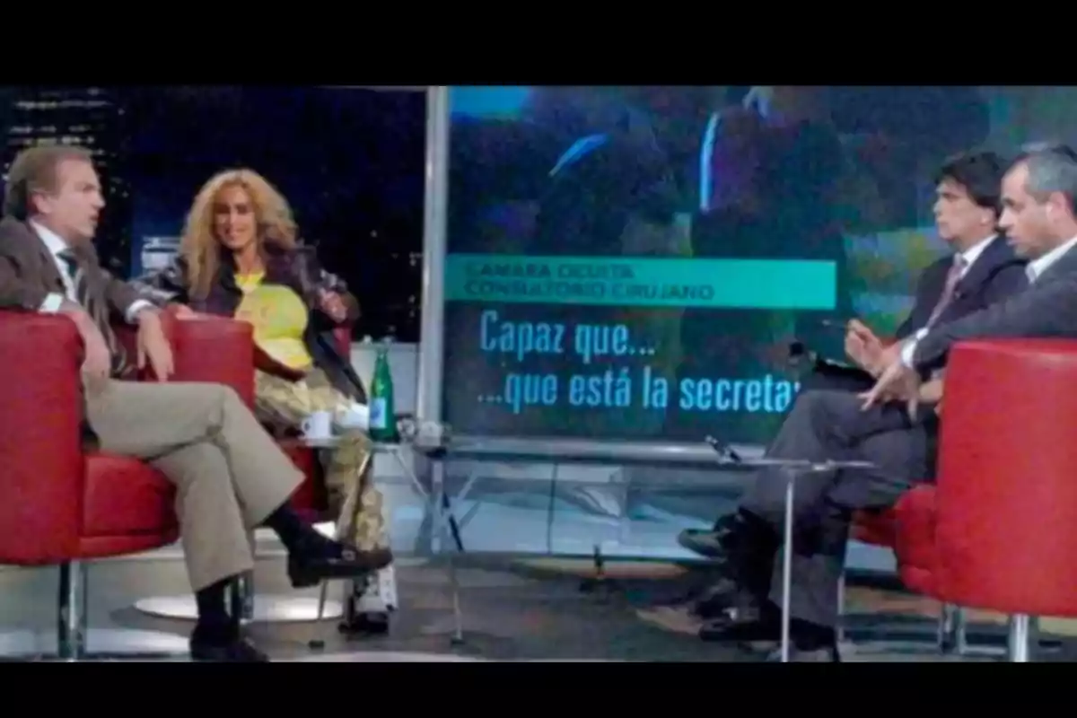 Cuatro personas sentadas en sillones rojos participan en un programa de televisión con una pantalla de fondo que muestra texto y gráficos. Cuatro personas sentadas en sillones rojos participan en un programa de televisión con una pantalla de fondo que muestra texto y gráficos.