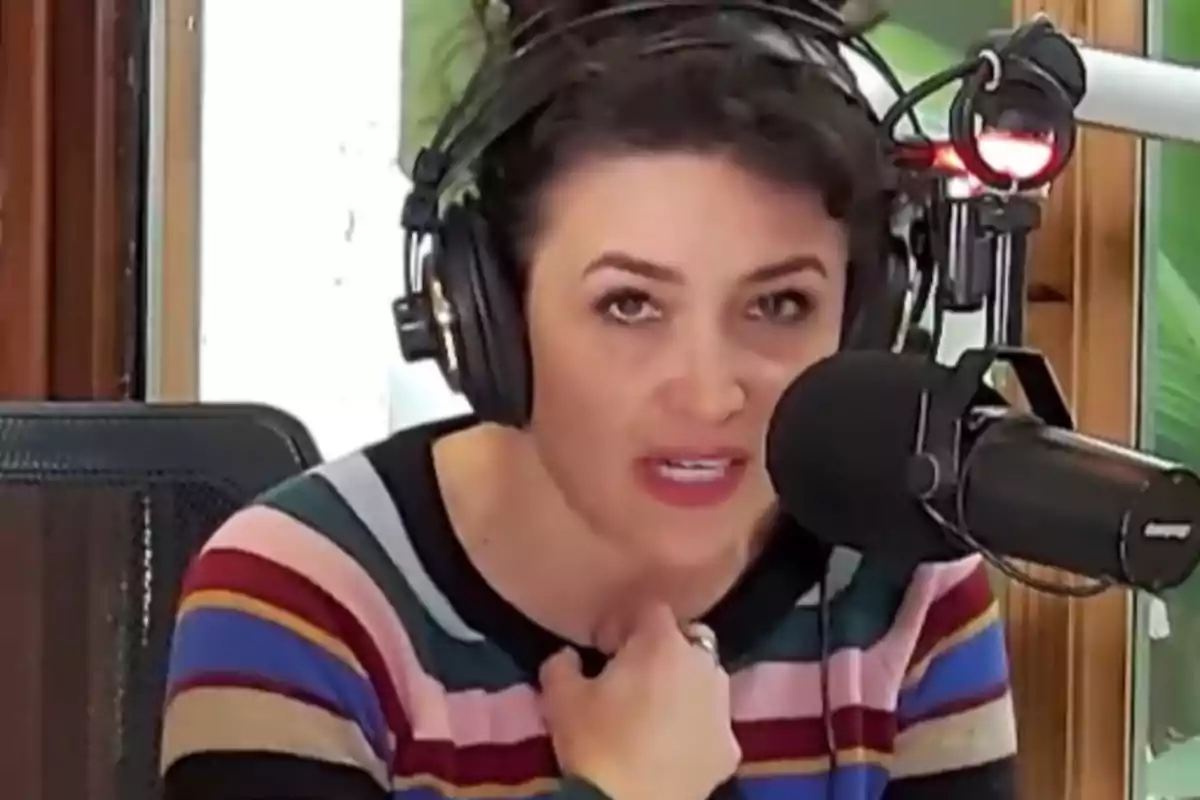 Woman wearing headphones speaking into a microphone in a radio booth, wearing a colorful striped sweater. Woman wearing headphones speaking into a microphone in a radio booth, wearing a colorful striped sweater.