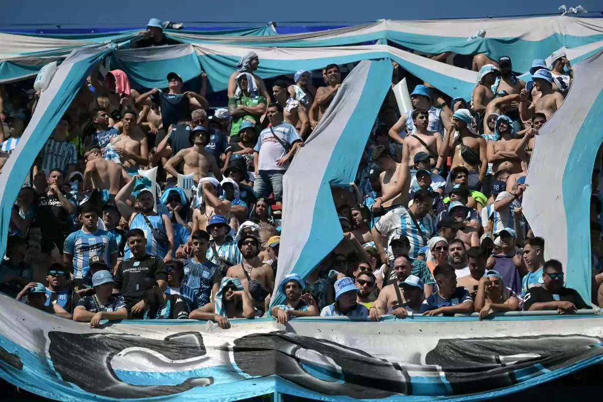 Racing Club fans cheer in the stands wearing sky blue and white jerseys, waving flags and hats under the sun. Racing Club fans cheer in the stands wearing sky blue and white jerseys, waving flags and hats under the sun.