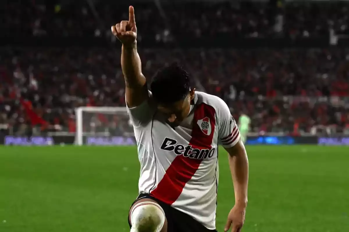 Futbolista de River Plate celebrando un gol en el campo señalando al cielo con el dedo índice mientras se arrodilla Futbolista de River Plate celebrando un gol en el campo señalando al cielo con el dedo índice mientras se arrodilla