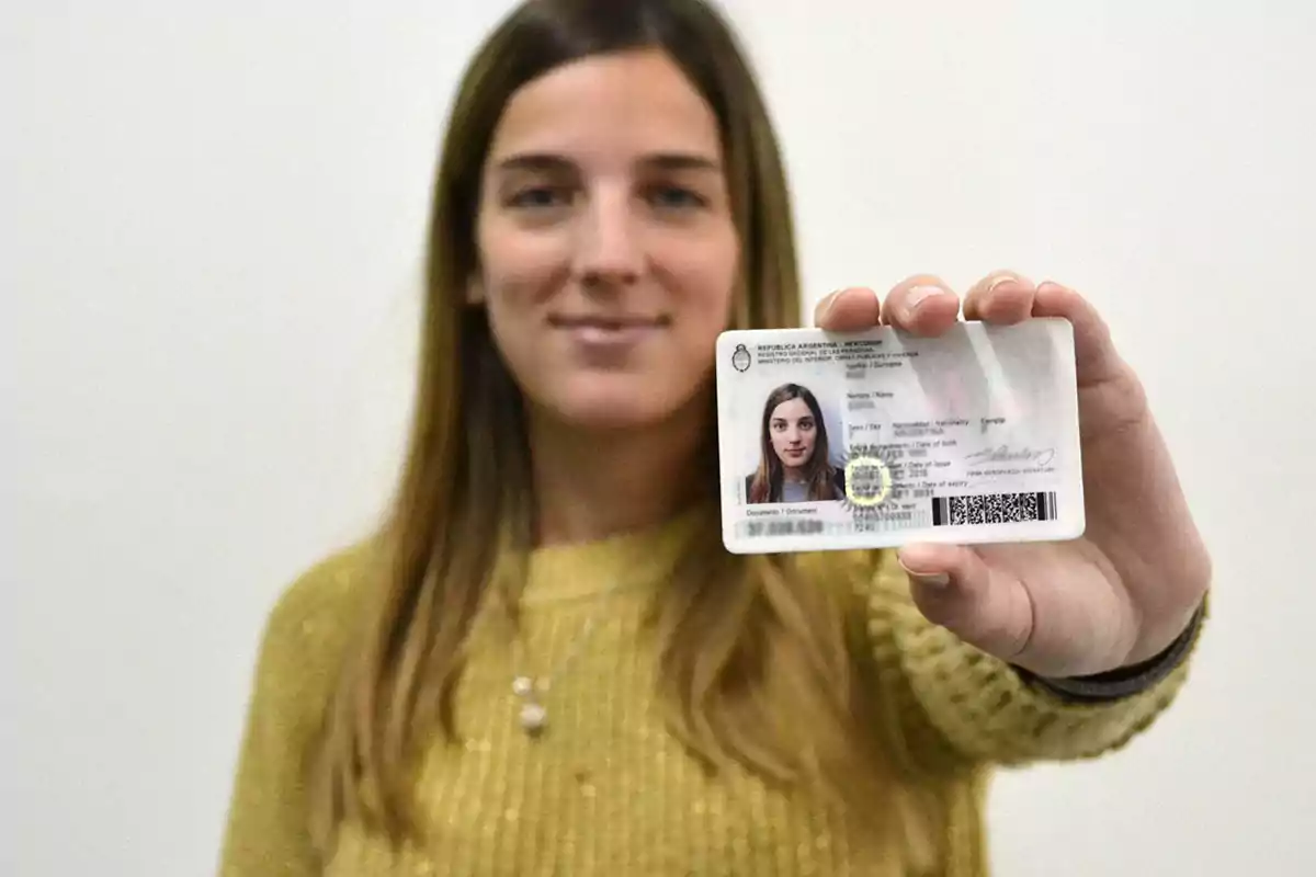 Young woman in a yellow sweater holding an Argentine ID card in front of the camera Young woman in a yellow sweater holding an Argentine ID card in front of the camera