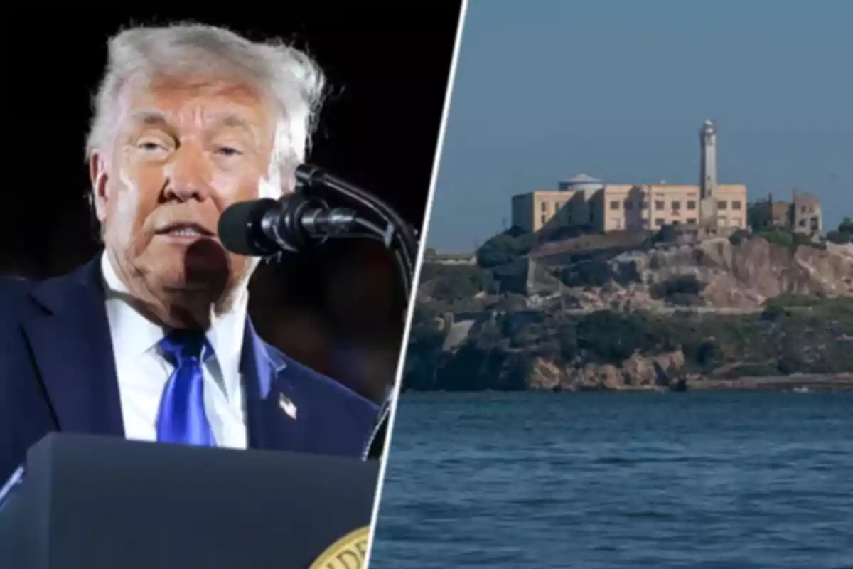 A gray-haired man speaking in front of a microphone, with an image of a prison on an island surrounded by water in the background.