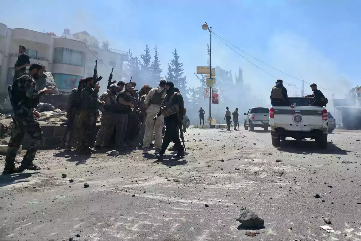 Group of armed soldiers gathered on a street with smoke and debris as a military truck moves near them Group of armed soldiers gathered on a street with smoke and debris as a military truck moves near them