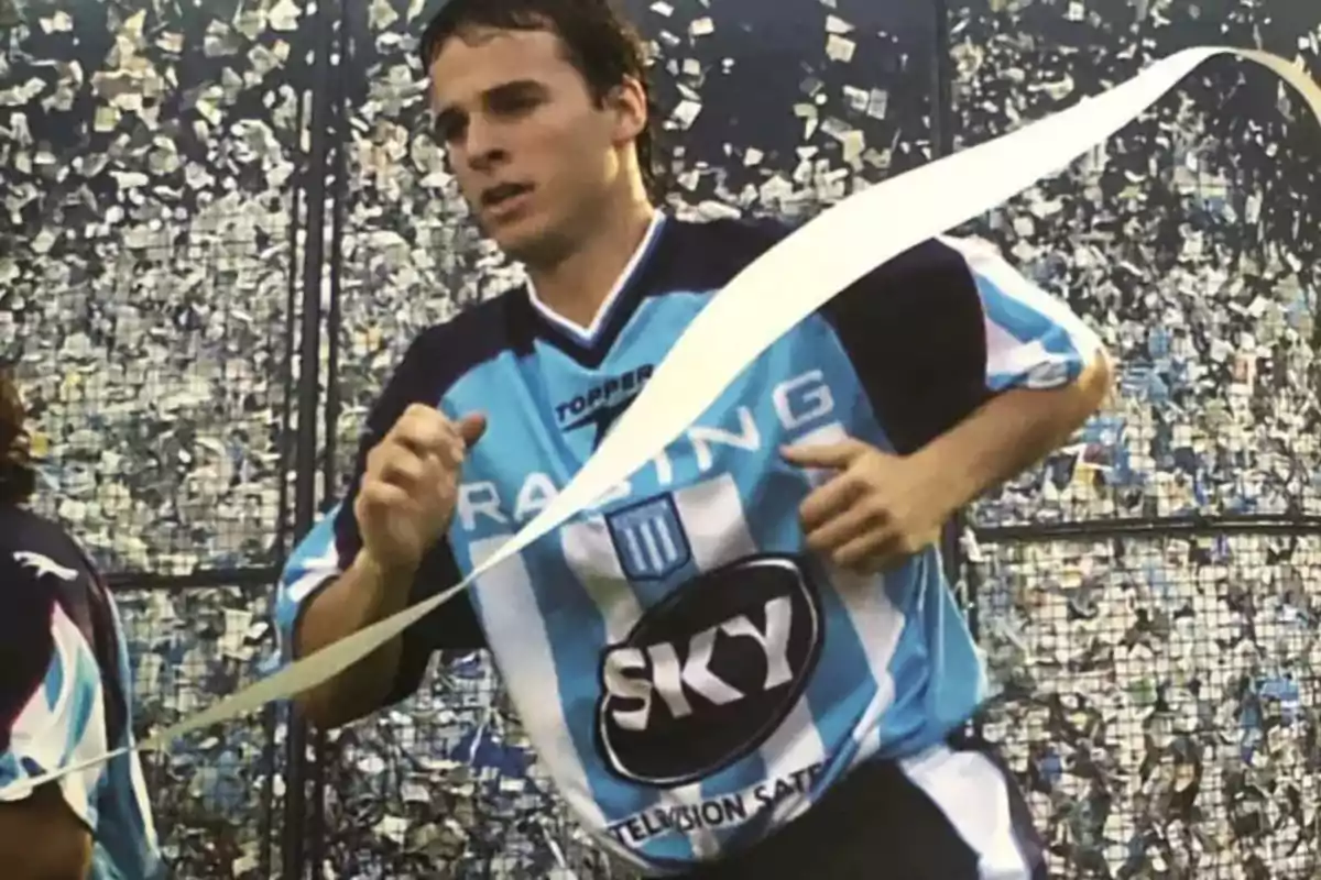 Futbolista con camiseta de Racing Club corriendo en la cancha con papelitos y una serpentina en el aire Futbolista con camiseta de Racing Club corriendo en la cancha con papelitos y una serpentina en el aire