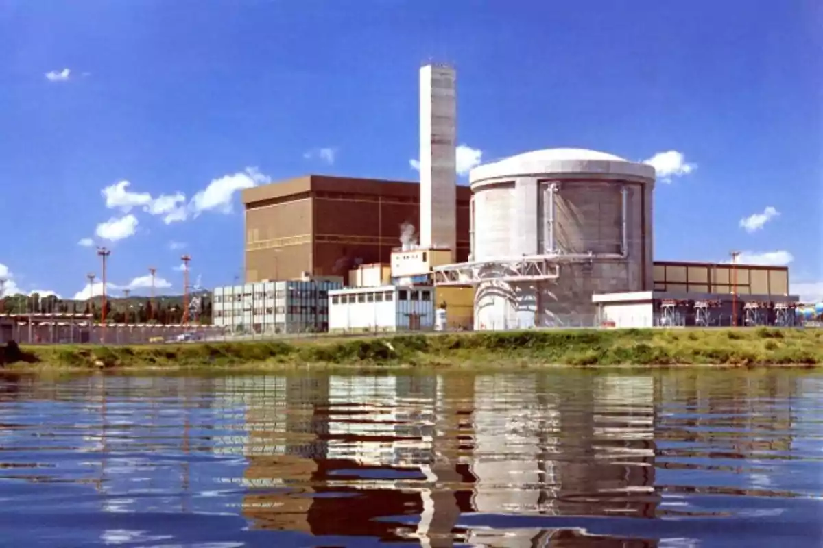 Central nuclear junto a un cuerpo de agua con cielo despejado y reflejo en el agua Central nuclear junto a un cuerpo de agua con cielo despejado y reflejo en el agua