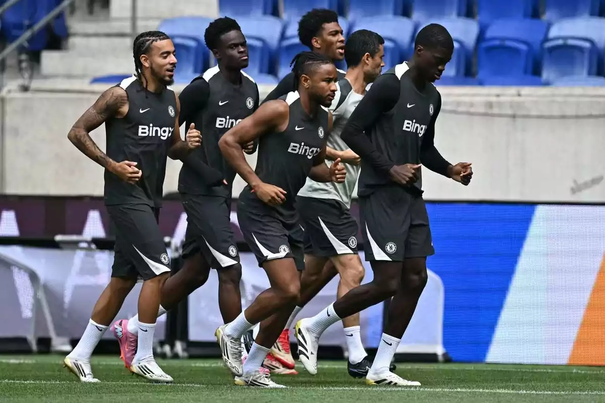Chelsea football players training together on a field wearing black training uniforms with the Bing logo on their chests