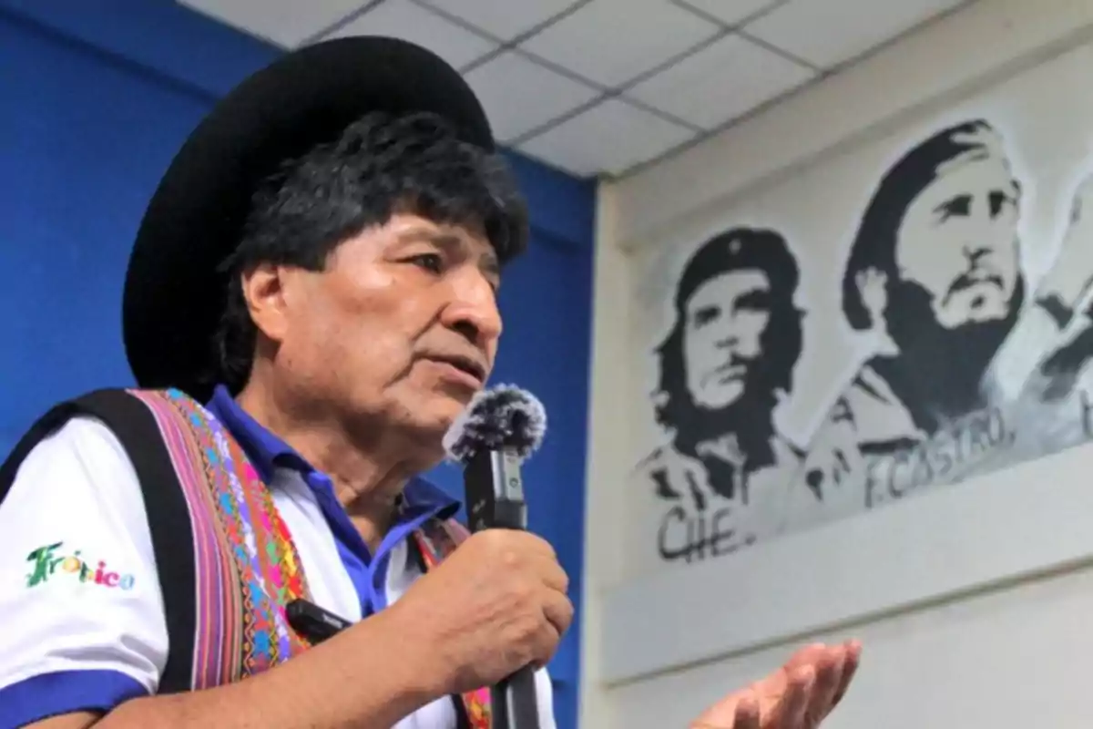 Hombre con sombrero y vestimenta tradicional hablando con micrófono en mano mientras al fondo se observa un mural con los rostros de Che Guevara y Fidel Castro