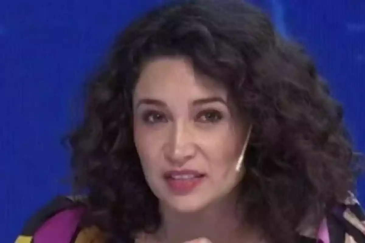 Mujer de cabello rizado usando micrófono de diadema frente a un fondo azul