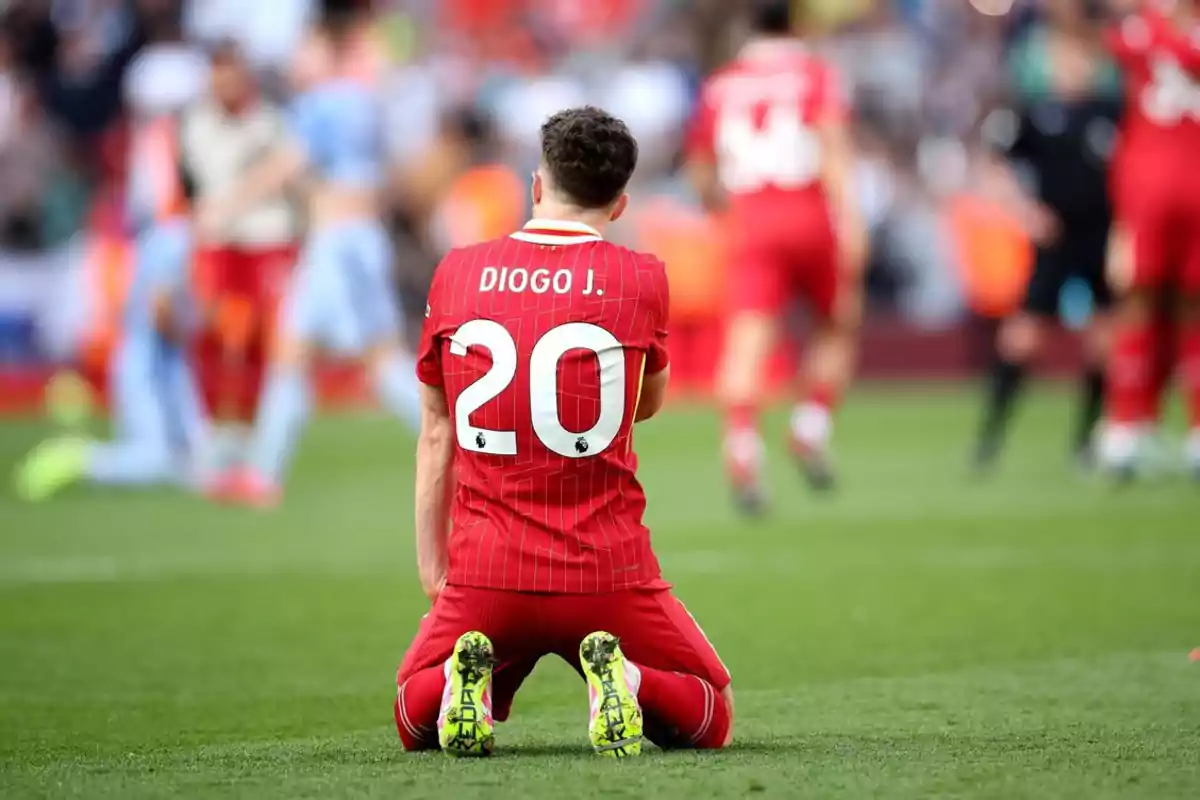 Futbolista con el número 20 y el nombre Diogo J en la camiseta arrodillado en el campo durante un partido