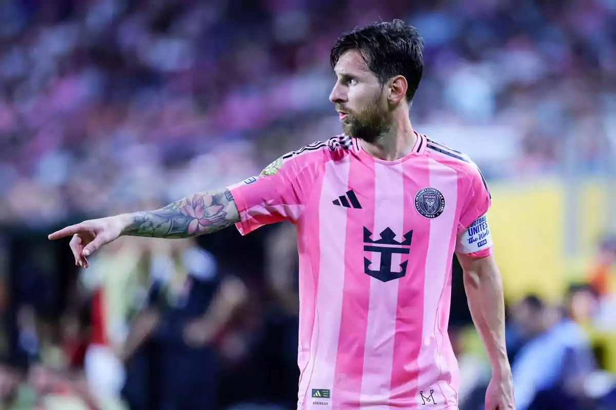 Soccer player in a pink uniform pointing with an outstretched arm during a match