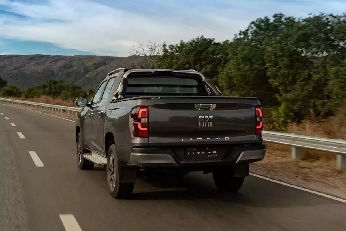Camioneta Fiat Titano gris circulando por una carretera rodeada de vegetación y montañas al fondo