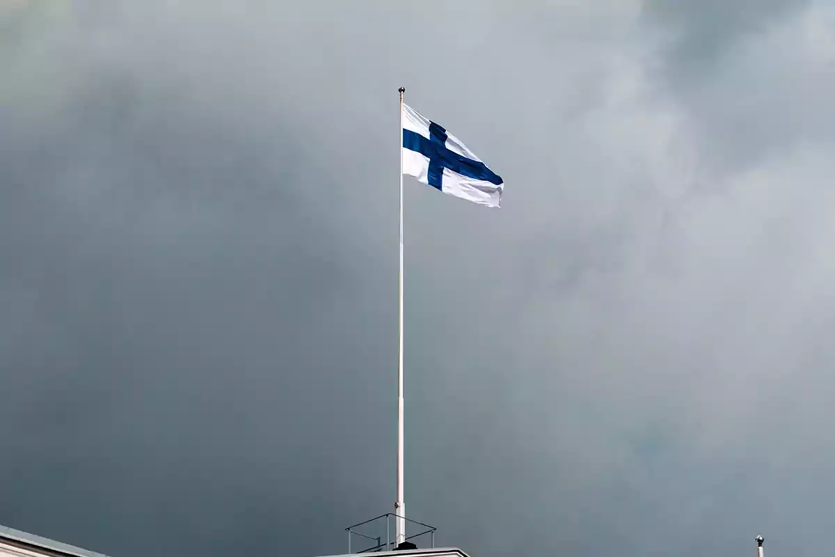 Bandera de Finlandia ondeando en un mástil bajo un cielo nublado Bandera de Finlandia ondeando en un mástil bajo un cielo nublado