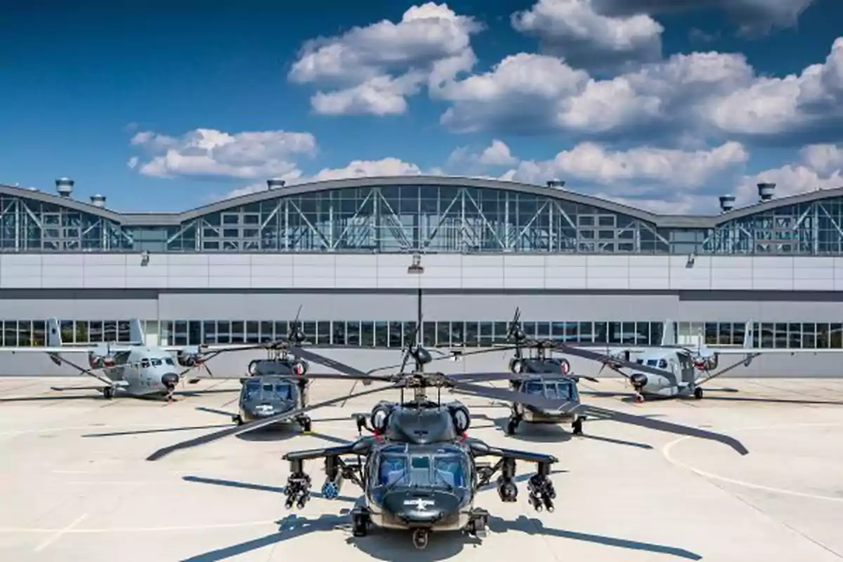 Four military helicopters and two light aircraft are parked in front of a modern hangar under a blue sky with fluffy clouds. Four military helicopters and two light aircraft are parked in front of a modern hangar under a blue sky with fluffy clouds.