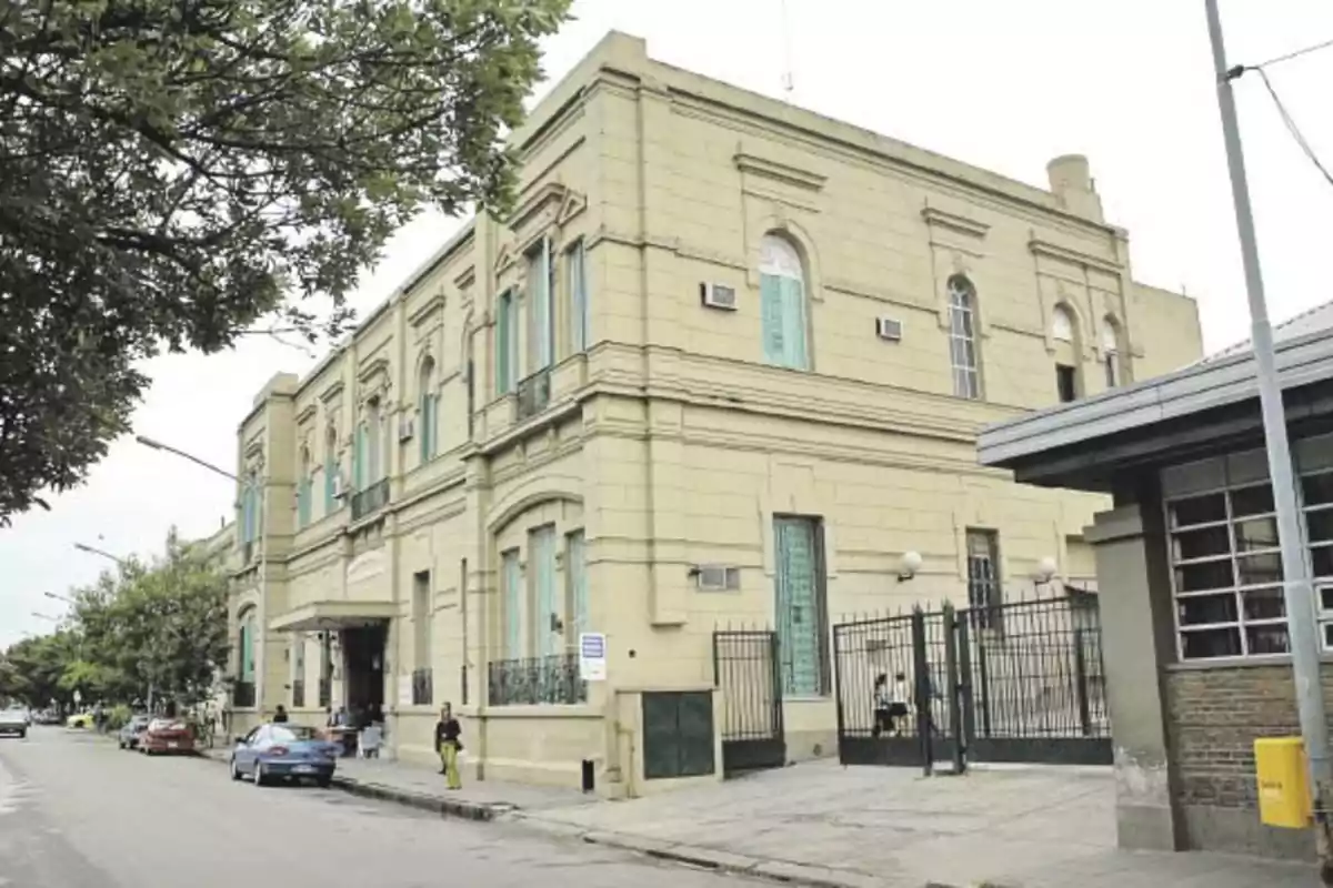 Edificio antiguo de dos pisos con ventanas altas y rejas en la entrada principal ubicado en una esquina de una calle urbana Edificio antiguo de dos pisos con ventanas altas y rejas en la entrada principal ubicado en una esquina de una calle urbana