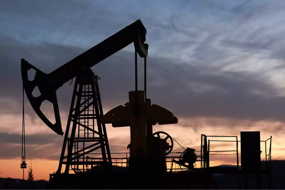 Bomba extractora de petróleo en silueta durante el atardecer Bomba extractora de petróleo en silueta durante el atardecer