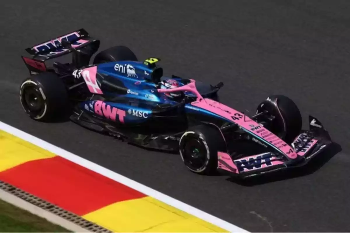 Auto de Fórmula 1 de color azul y rosa circulando en una pista de carreras Auto de Fórmula 1 de color azul y rosa circulando en una pista de carreras