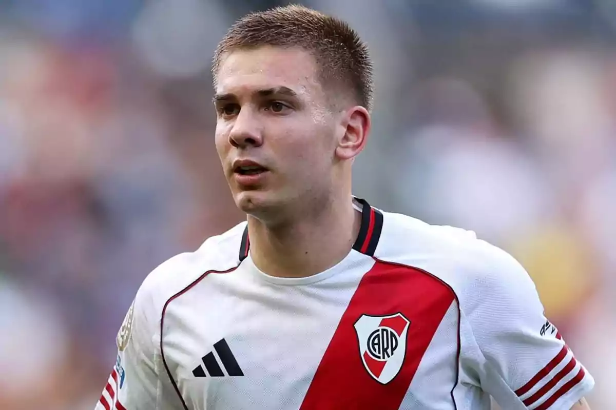 Soccer player wearing River Plate’s white jersey with a red sash during a match