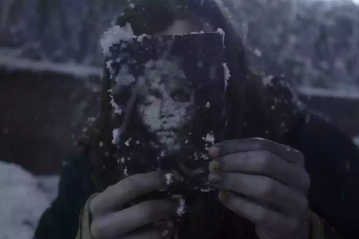 Persona sostiene una fotografía cubierta de nieve en un entorno invernal oscuro Persona sostiene una fotografía cubierta de nieve en un entorno invernal oscuro