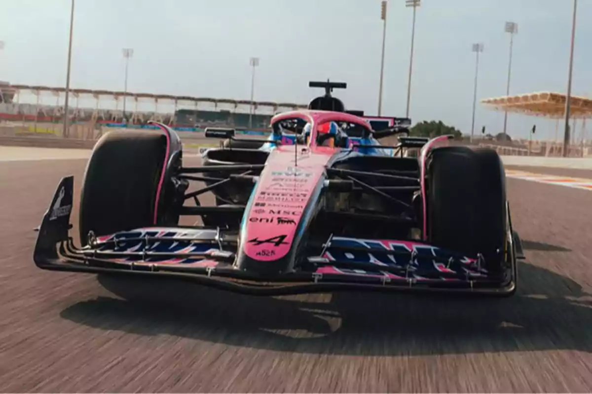 A pink and blue Formula 1 car speeds along a racetrack under a clear sky. A pink and blue Formula 1 car speeds along a racetrack under a clear sky.