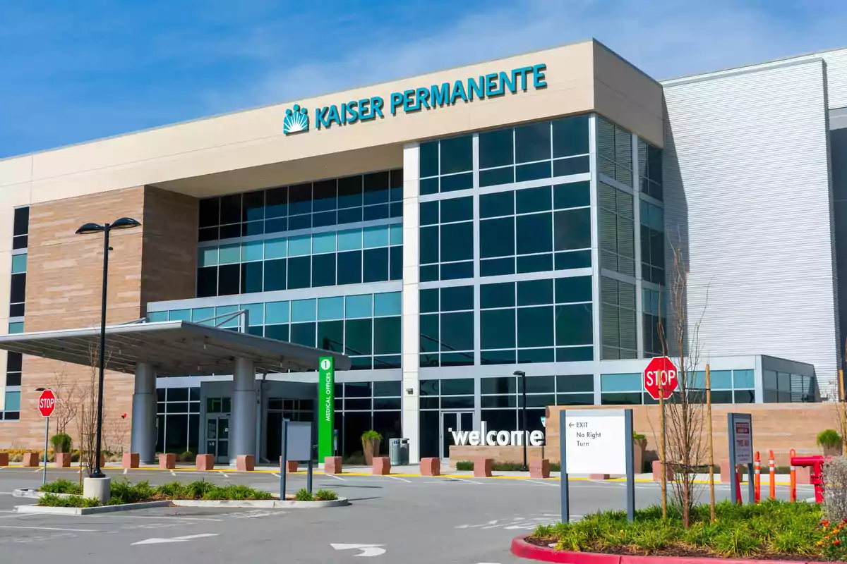 Facade of a modern Kaiser Permanente building with glass windows and traffic signs in the parking lot Facade of a modern Kaiser Permanente building with glass windows and traffic signs in the parking lot
