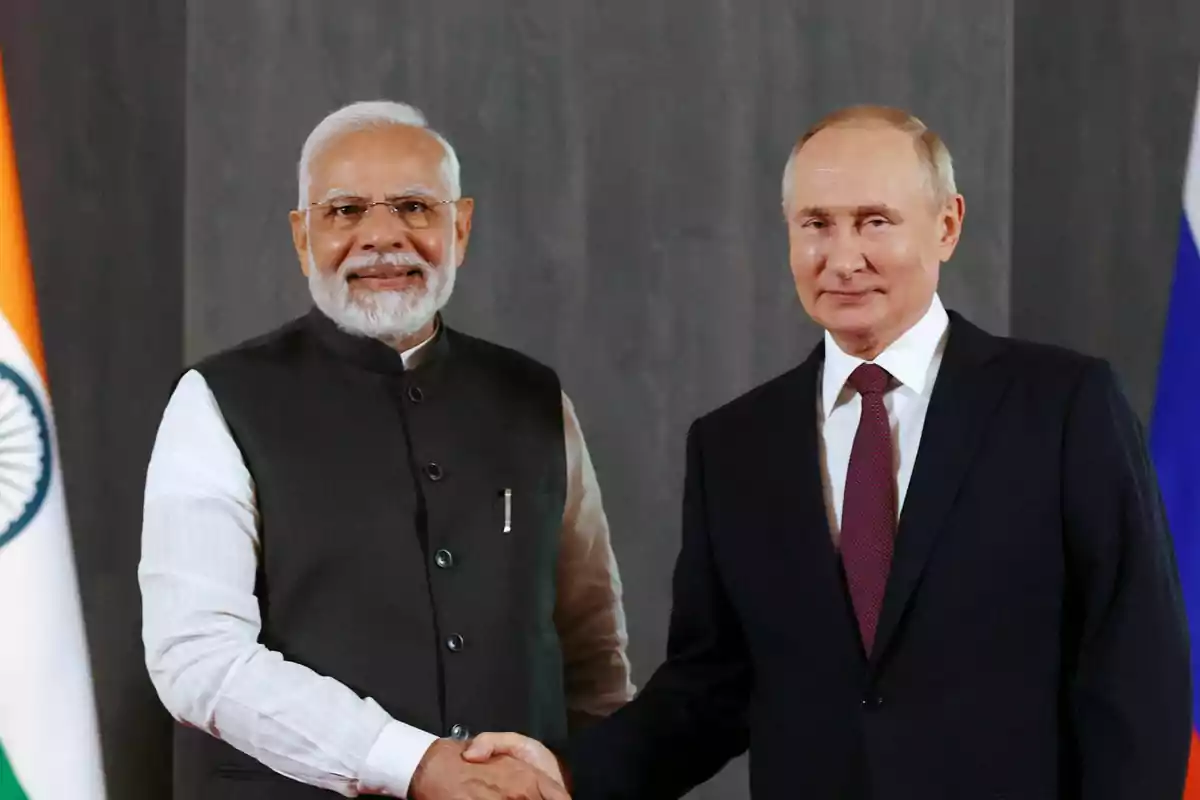 Dos hombres de traje se dan la mano frente a las banderas de la India y Rusia
