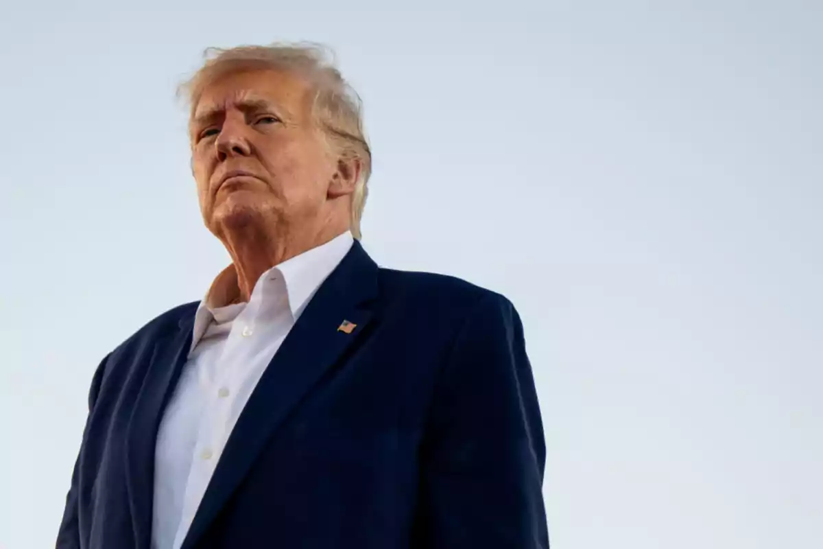 Blond-haired man in a blue suit and white jersey looking toward the horizon with a serious expression against a clear sky background Blond-haired man in a blue suit and white jersey looking toward the horizon with a serious expression against a clear sky background