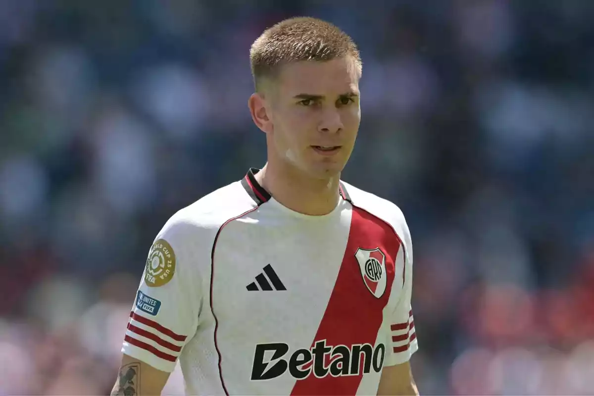 Soccer player wearing a white River Plate jersey with a red stripe in a stadium