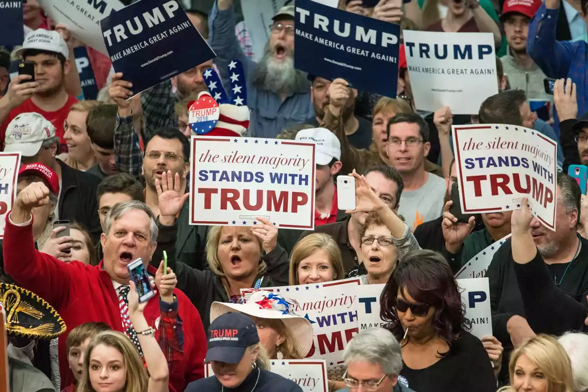 Multitud de personas en un mitin político sosteniendo carteles de apoyo a Donald Trump y usando gorras y camisetas alusivas Multitud de personas en un mitin político sosteniendo carteles de apoyo a Donald Trump y usando gorras y camisetas alusivas