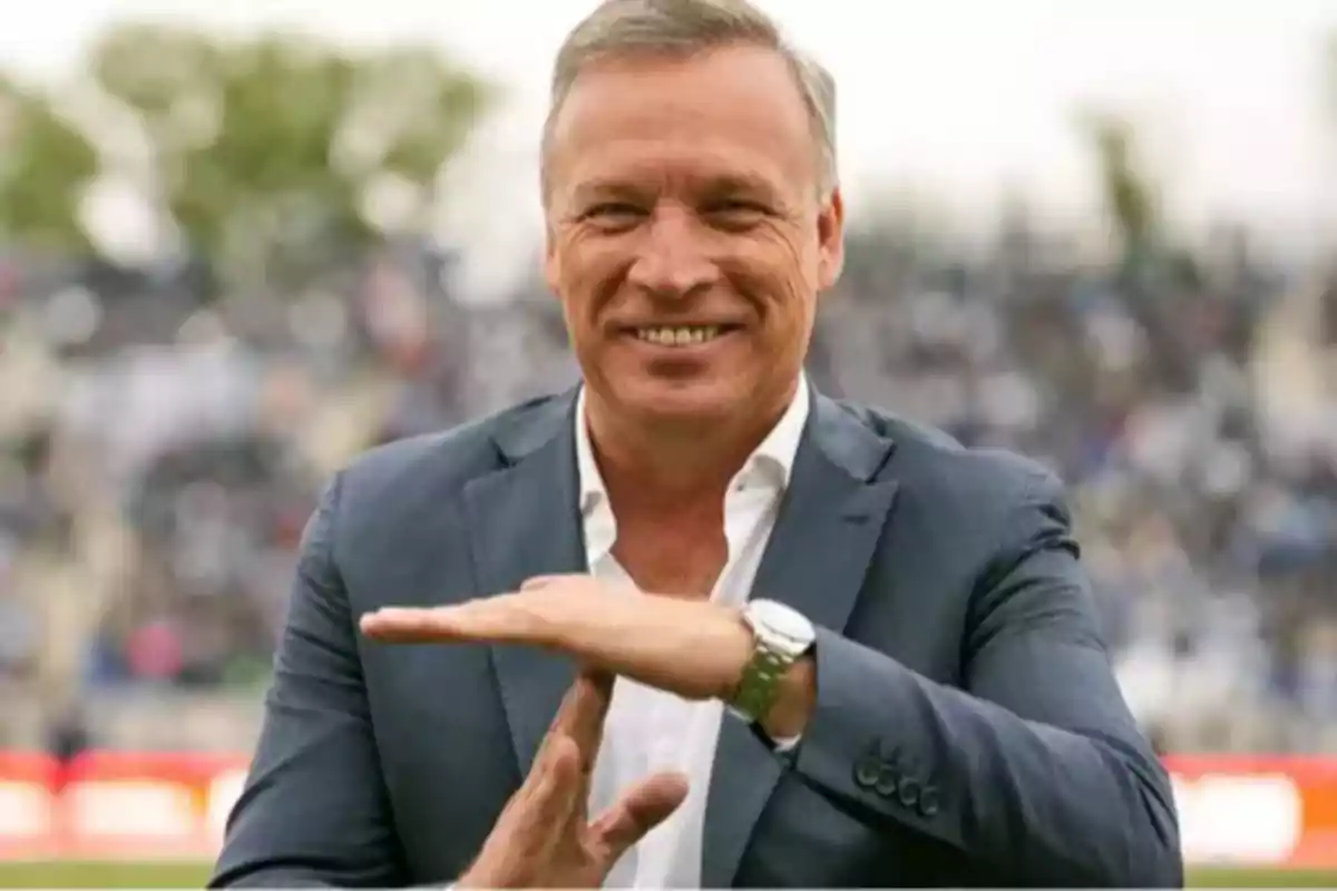 Smiling man in a suit making the timeout gesture with his hands in an outdoor stadium Smiling man in a suit making the timeout gesture with his hands in an outdoor stadium