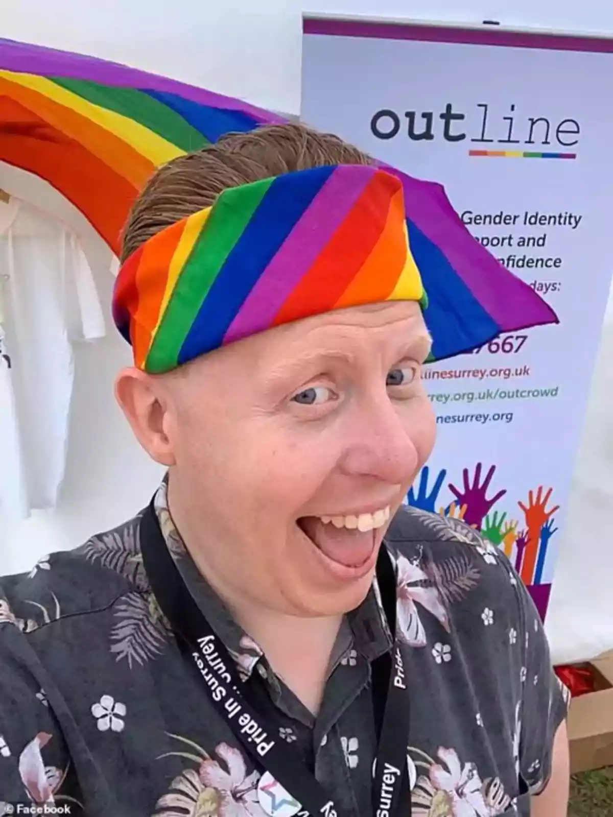 Persona sonriente con una banda de colores del arcoíris en la cabeza, frente a un cartel de apoyo a la diversidad y la identidad de género Persona sonriente con una banda de colores del arcoíris en la cabeza, frente a un cartel de apoyo a la diversidad y la identidad de género
