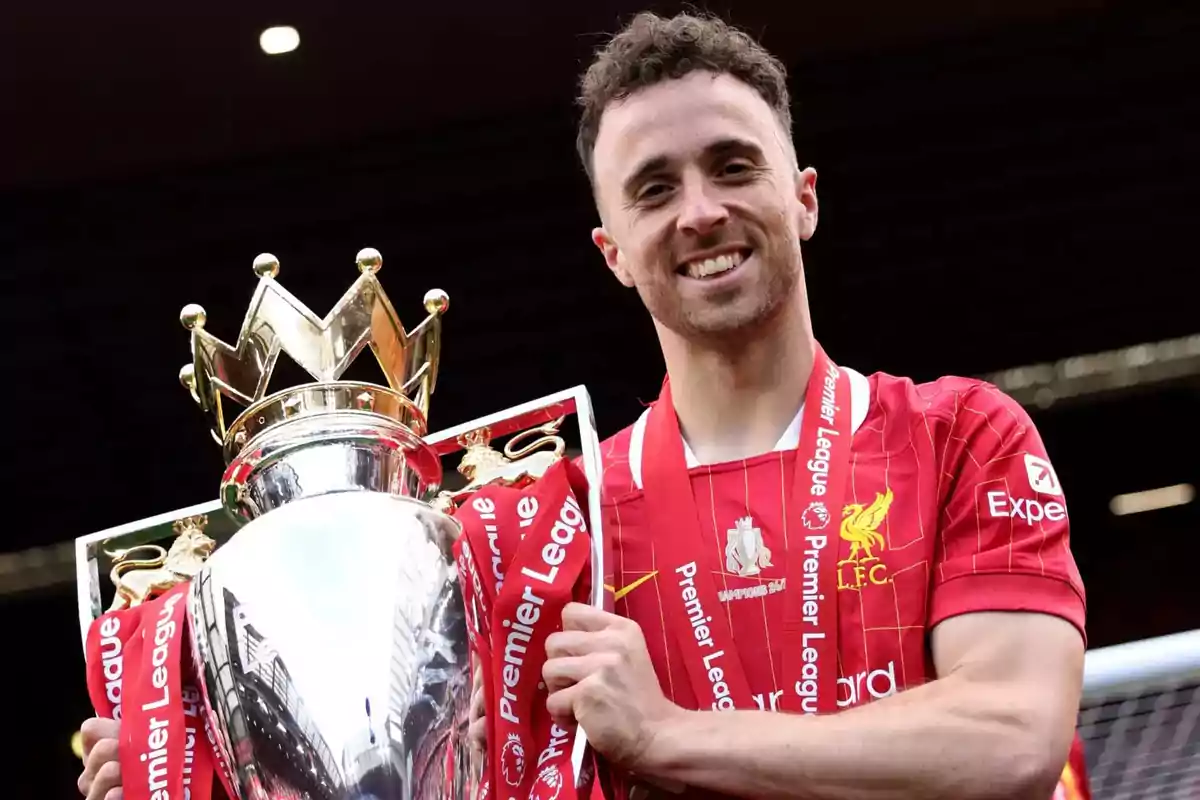 Liverpool footballer smiles while holding the Premier League trophy Liverpool footballer smiles while holding the Premier League trophy