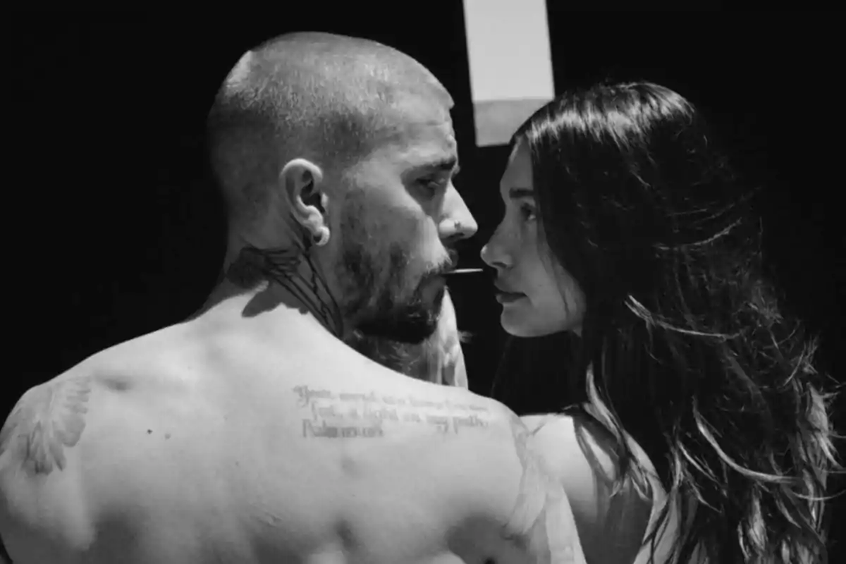 Couple looking closely at each other in black and white with serious expressions and a dark background Couple looking closely at each other in black and white with serious expressions and a dark background