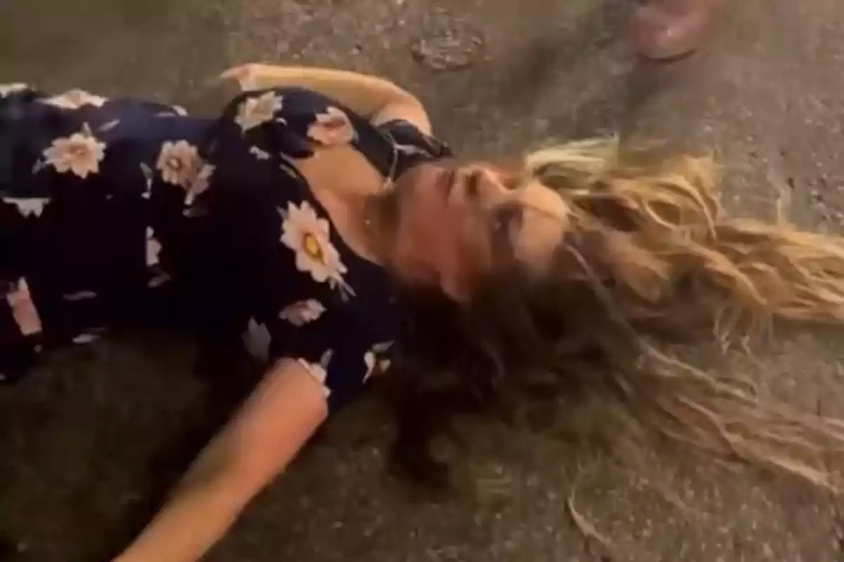 Mujer con vestido azul de flores acostada en el suelo con expresión de desconcierto Mujer con vestido azul de flores acostada en el suelo con expresión de desconcierto