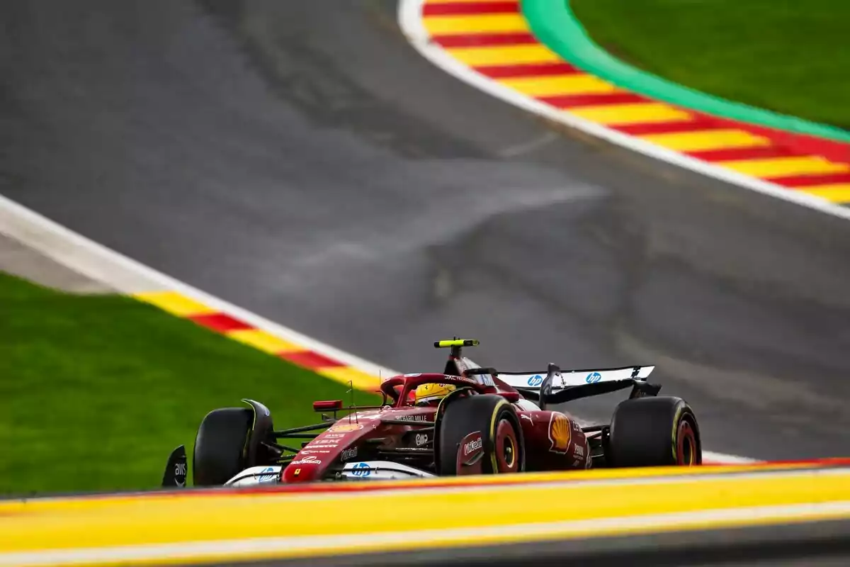 Un auto de Fórmula 1 rojo circula por una pista con bordes amarillos y rojos y césped verde alrededor Un auto de Fórmula 1 rojo circula por una pista con bordes amarillos y rojos y césped verde alrededor