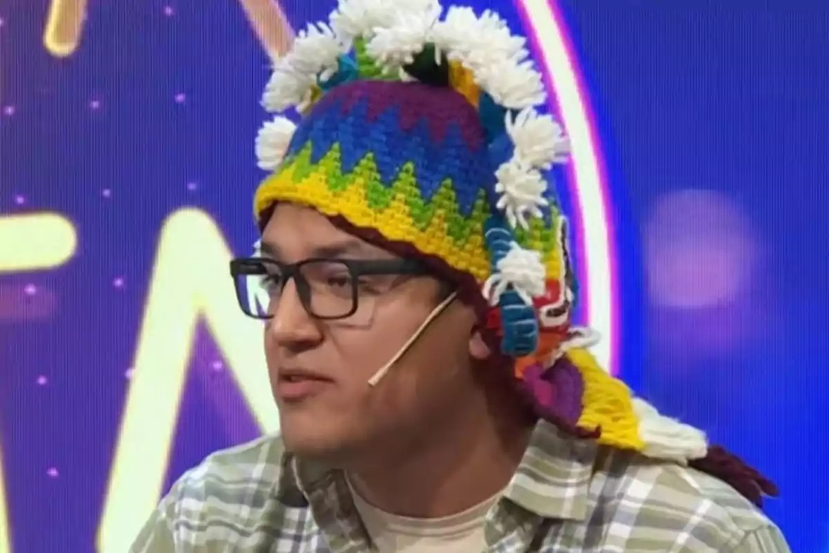 Hombre con gafas y gorro andino multicolor hablando en un programa de televisión