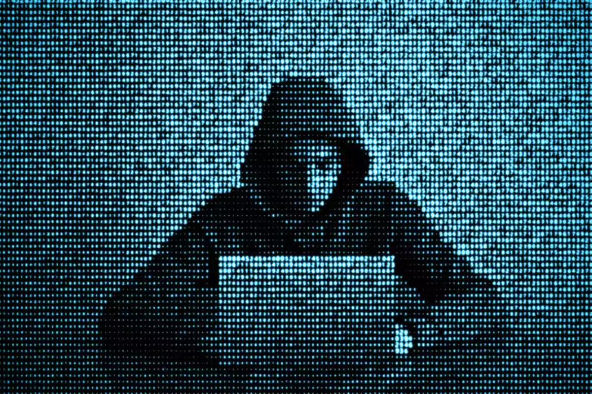 Person wearing a hoodie using a laptop depicted with a blue digital dot effect