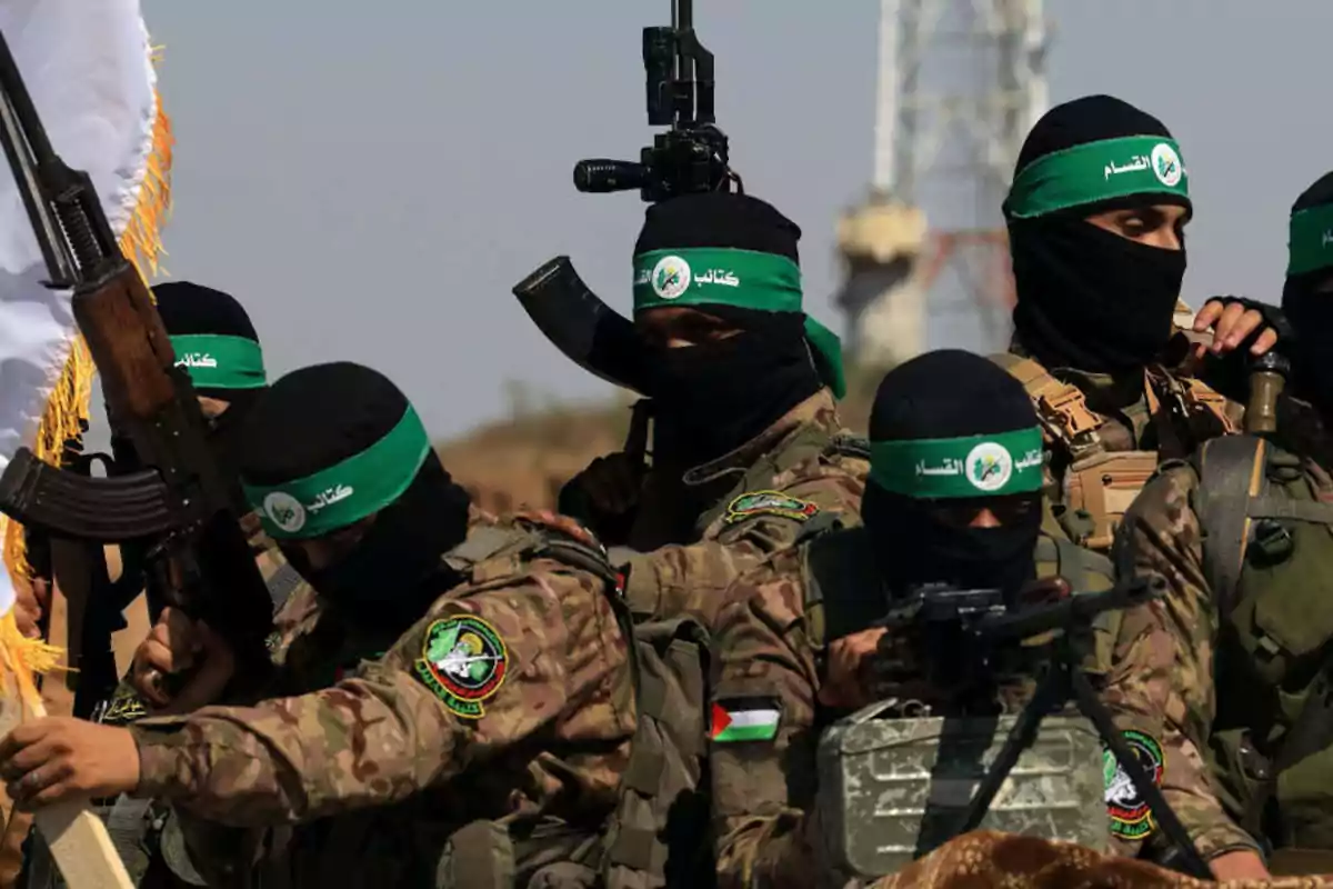 Grupo de hombres armados con uniformes de camuflaje y pasamontañas negros con cintas verdes en la cabeza Grupo de hombres armados con uniformes de camuflaje y pasamontañas negros con cintas verdes en la cabeza