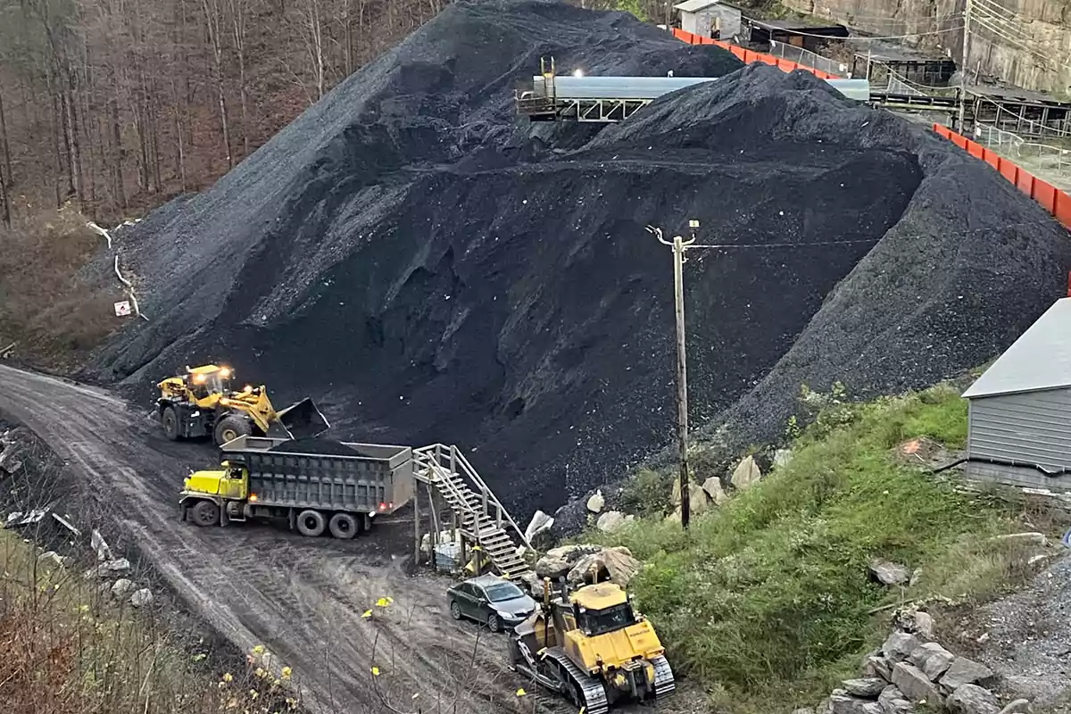Coal mountain with heavy machinery and a truck working in an open-pit mine Coal mountain with heavy machinery and a truck working in an open-pit mine