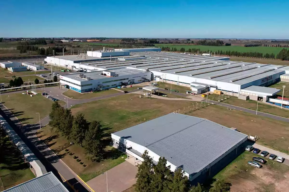Vista aérea de una gran planta industrial rodeada de áreas verdes y estacionamientos Vista aérea de una gran planta industrial rodeada de áreas verdes y estacionamientos