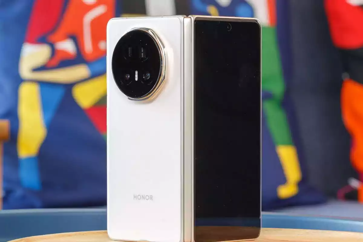 White Honor foldable phone with a large circular camera module on a table and a colorful blurred background White Honor foldable phone with a large circular camera module on a table and a colorful blurred background
