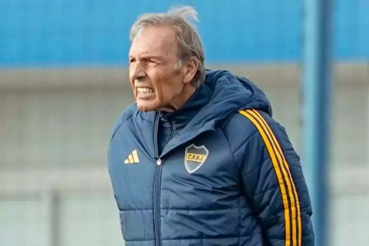 Hombre mayor con campera azul de Boca Juniors gesticulando en una cancha de fútbol Hombre mayor con campera azul de Boca Juniors gesticulando en una cancha de fútbol