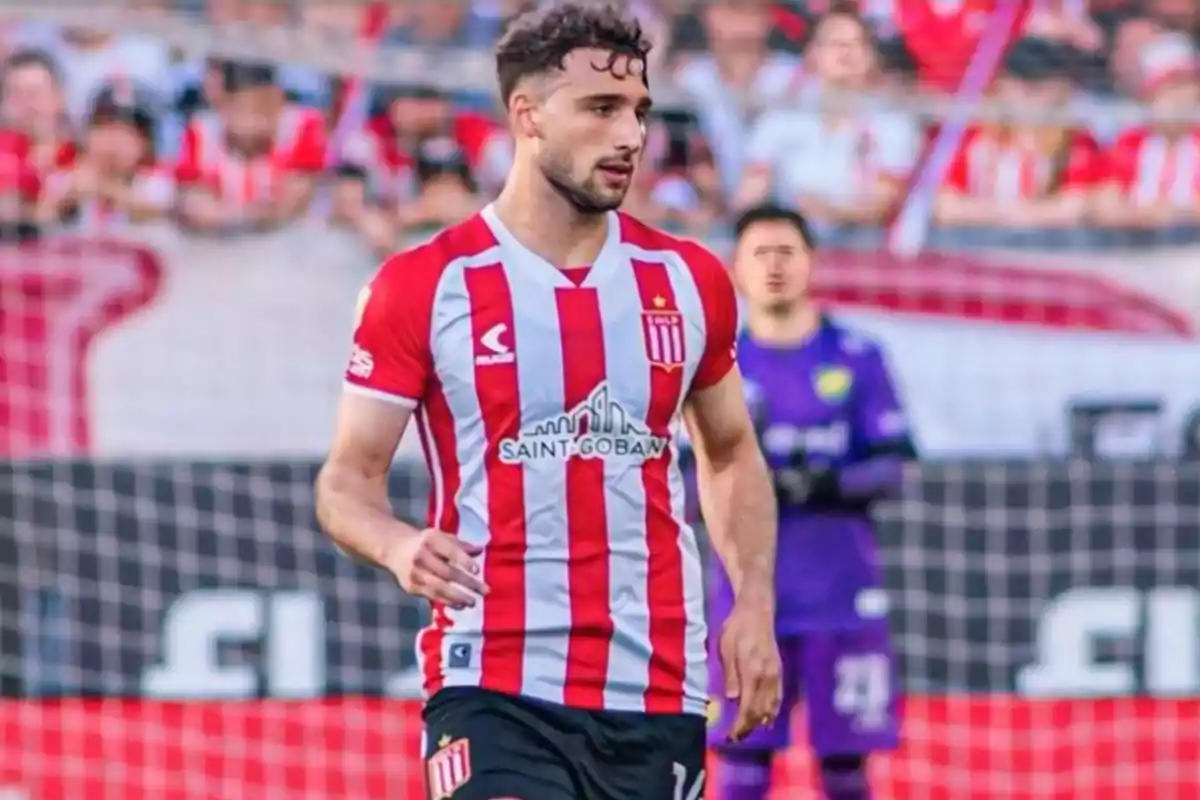 Soccer player wearing a red and white striped uniform in a stadium during a match