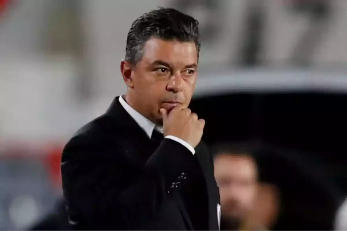 Short dark-haired man dressed in a black suit in a thoughtful attitude