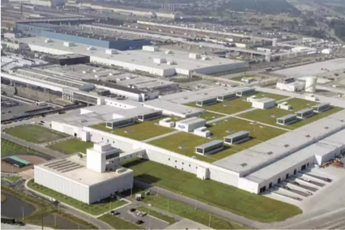 Vista aérea de una gran planta industrial con techos verdes y varias edificaciones rodeadas de áreas verdes y caminos. Vista aérea de una gran planta industrial con techos verdes y varias edificaciones rodeadas de áreas verdes y caminos.