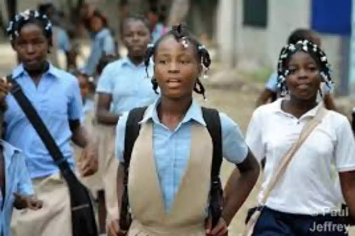 Grupo de niñas con uniforme escolar caminando al aire libre llevando mochilas y bolsos