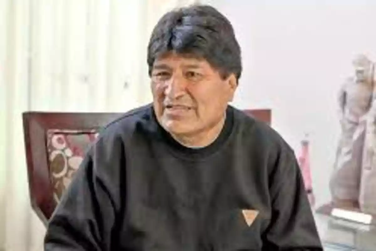Dark-haired man with short hair wearing a black sweater sitting on a chair inside a well-lit room Dark-haired man with short hair wearing a black sweater sitting on a chair inside a well-lit room