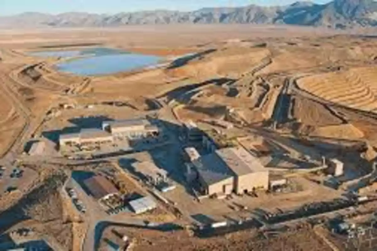 Aerial view of an open-pit mine with industrial facilities and mountains in the background Aerial view of an open-pit mine with industrial facilities and mountains in the background