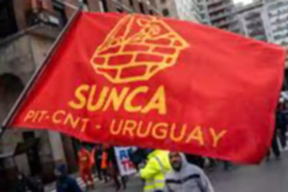 Bandera roja del sindicato SUNCA de Uruguay sostenida por manifestantes en una marcha urbana Bandera roja del sindicato SUNCA de Uruguay sostenida por manifestantes en una marcha urbana